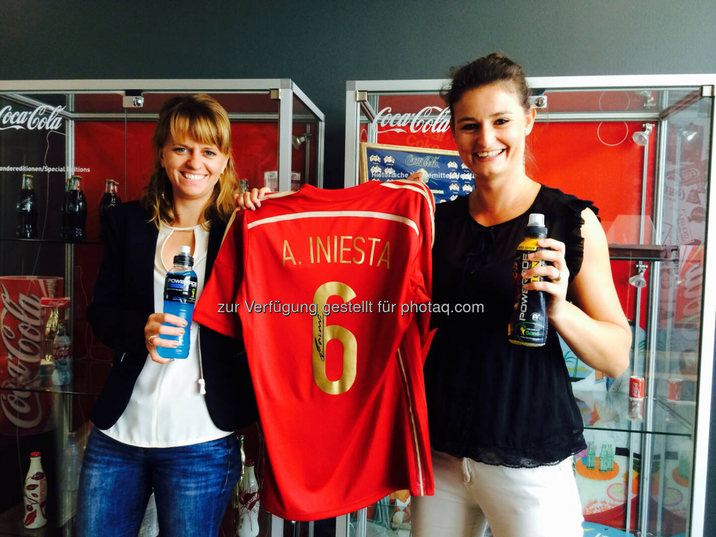 Nina Mahnik (links) mit ihrer Kollegin Lisa-Maria Moosbrugger, Powerade Brand Managerin in Österreich und Iniesta-Shirt – Powerade ermöglichet Fußballfans aus Österreich einen Traum und verlost 3x2 Tickets für ein internationales Meet & Greet mit Spaniens Superstar Andrés Iniesta in Barcelona inklusive MatchbesuchCredits: Coca-Cola