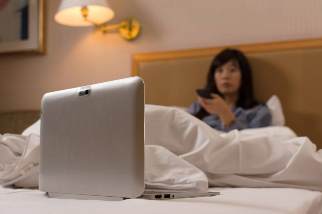 Fernsehen, Fernseher, Fernbedienung, TV, Television, fernschauen, Laptop, http://www.shutterstock.com/de/pic-207010474/stock-photo-asian-woman-put-her-laptop-on-bed-and-watch-tv-in-the-hotel.html, © www.shutterstock.com (12.11.2024) 