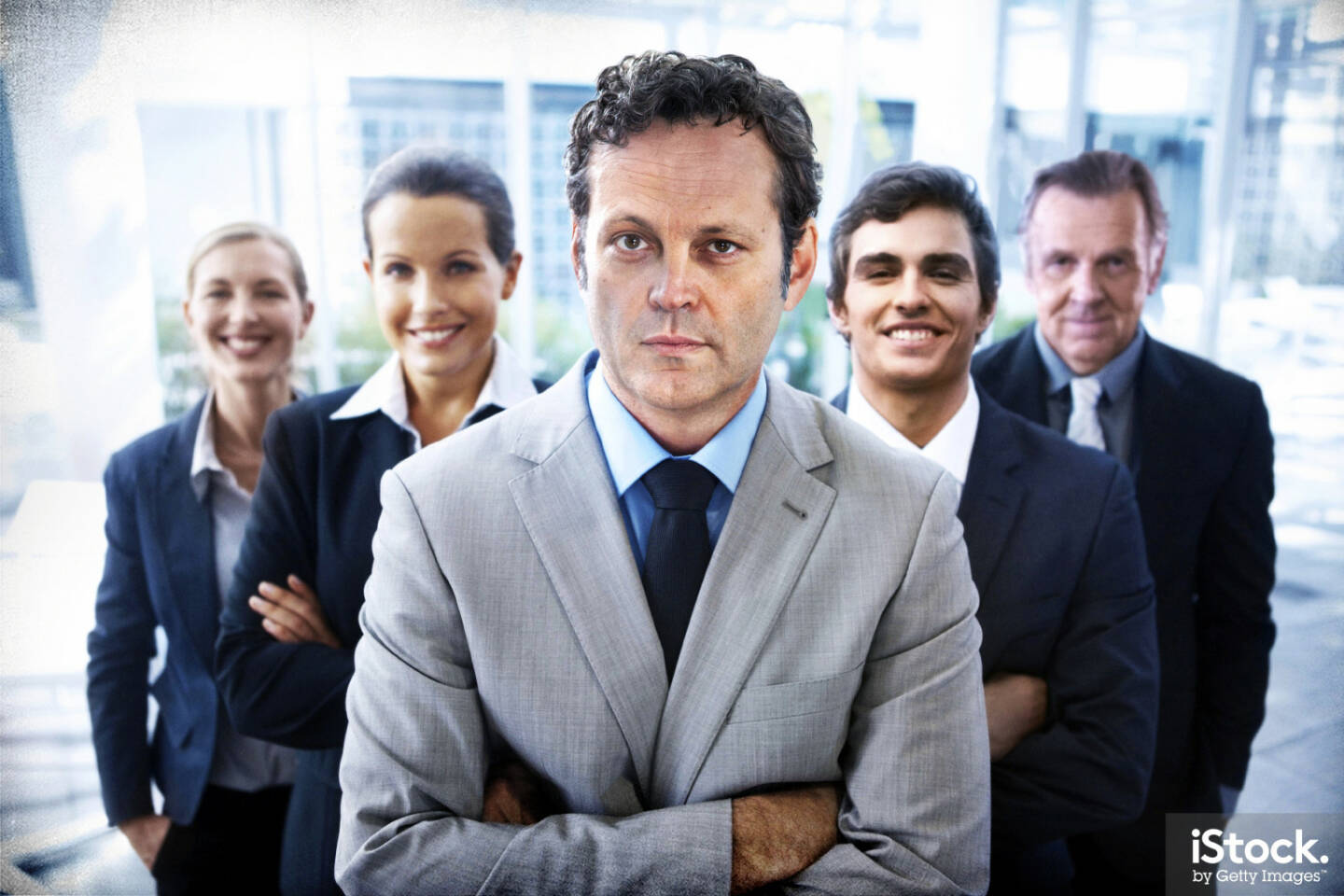 Vince Vaughn - Portrait of a handsome business leader crossing his arms with his team standing behind him - iStock, Getty Images