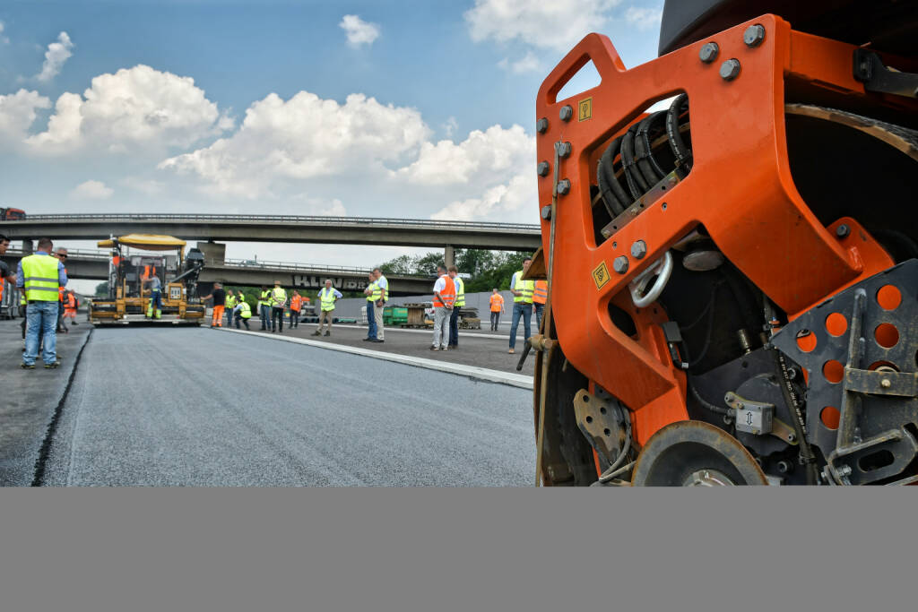 NaHiTAs (Nachhaltiger High-Tech Asphalt) - Das mit Titandioxid versetzte Granulat wird über den fertigerintegrierten Streuer (hinten im Bild) in die Asphaltdeckschicht eingebunden.
Bildnachweis: STRABAG AG, © Aussendung (06.02.2018) 